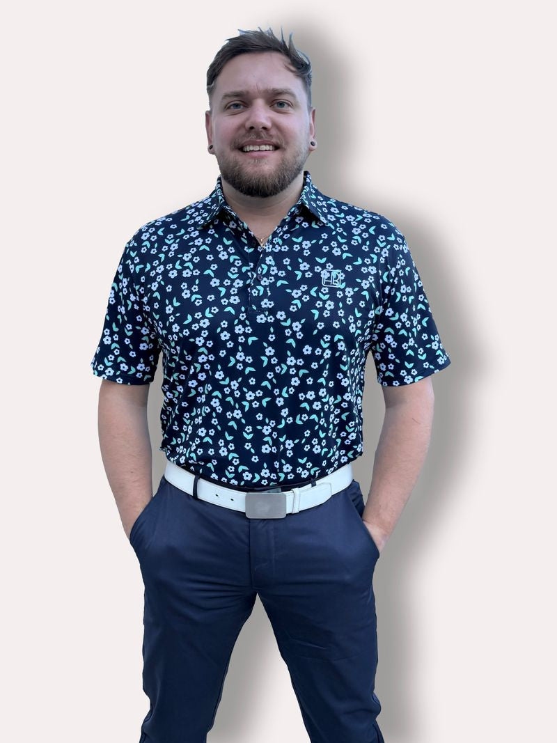 Mannequin portant un polo de golf bleu marine Hole Black imprimé Liberty fleurs blanches de face avec un pantalon de golf marine hole black