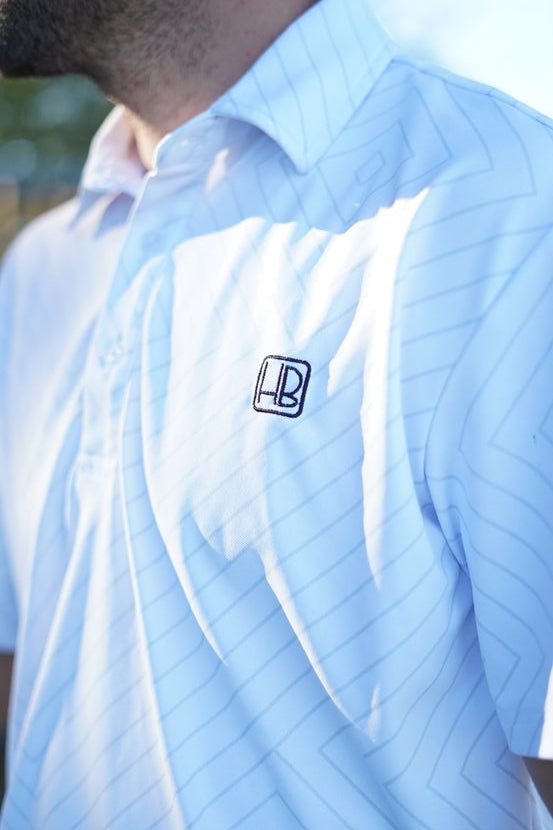 photo représentant un joueur de golf qui porte un polo de golf blanc à motif hole black sur un parcours