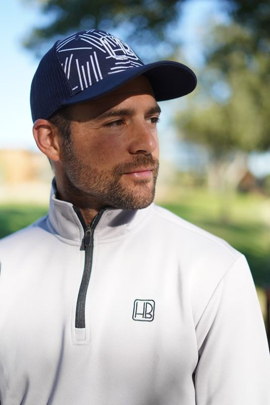 Joueur de golf portant un pull Hole Black gris et casquette de golf bleu, sweat avec zip fermeture eclair 1/4 extensible pour l'hiver, jouer au chaud